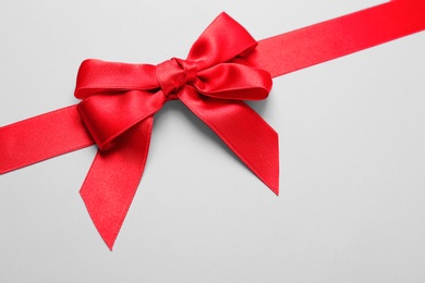 Photo of Beautiful red ribbon with bow on light background