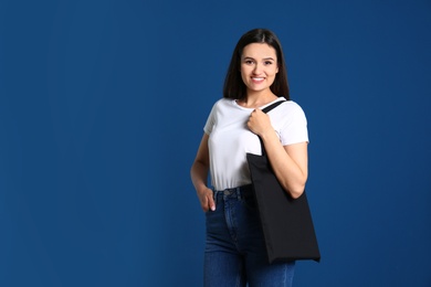 Beautiful young woman with stylish blank eco bag against color background, space for text