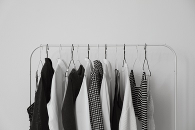 Photo of Rack with stylish clothes near white wall, closeup