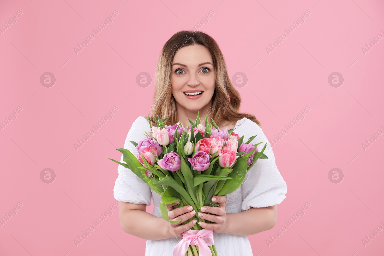 Photo of Happy young woman with bouquet of beautiful tulips on pink background