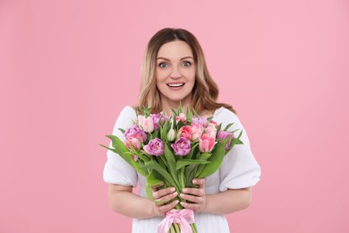 Photo of Happy young woman with bouquet of beautiful tulips on pink background