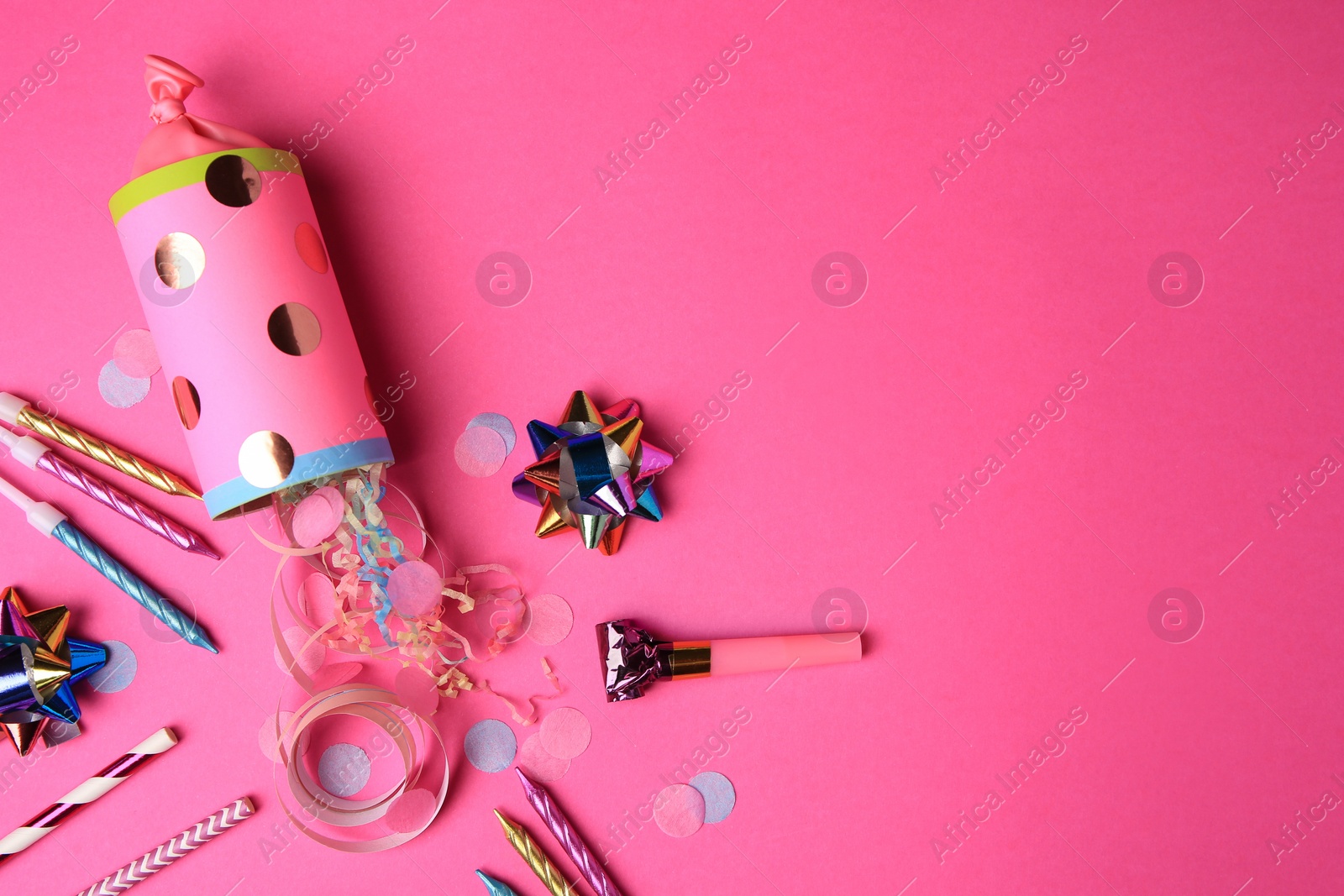 Photo of Party cracker and different festive items on bright pink background, flat lay. Space for text