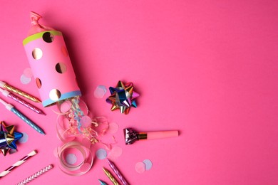 Party cracker and different festive items on bright pink background, flat lay. Space for text