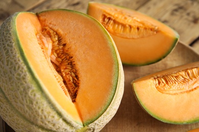 Photo of Tasty fresh cut melons on wooden tray, closeup