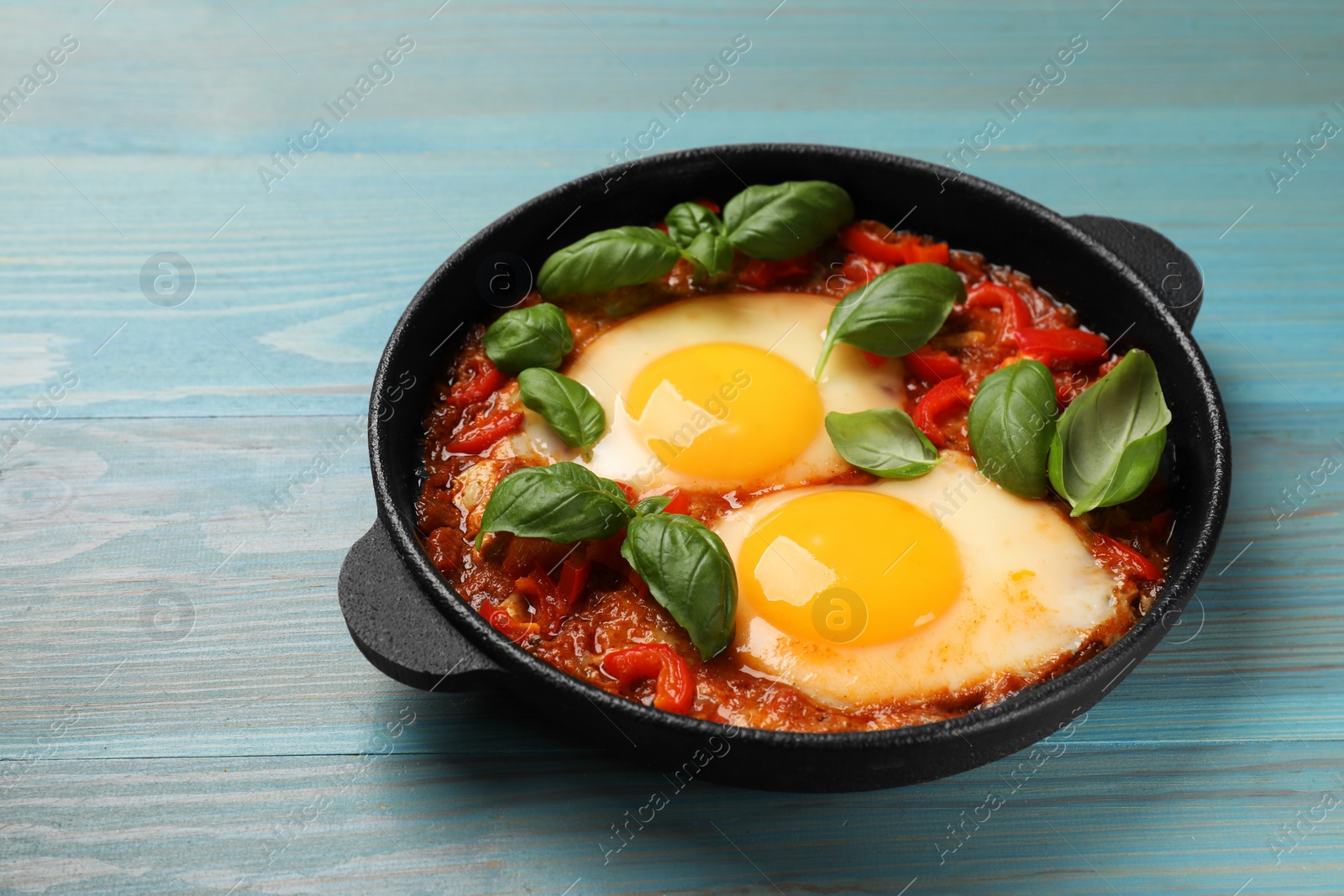 Photo of Delicious Shakshuka on light blue wooden table