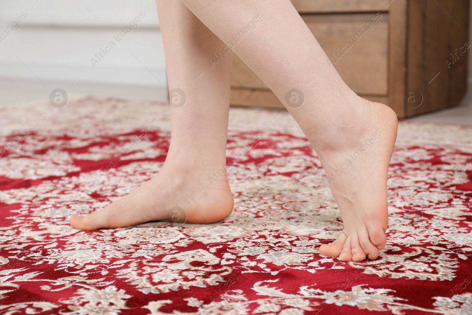 Photo of Woman standing on carpet with pattern at home, closeup