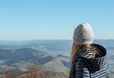Photo of Woman in warm clothes looking at beautiful mountain landscape
