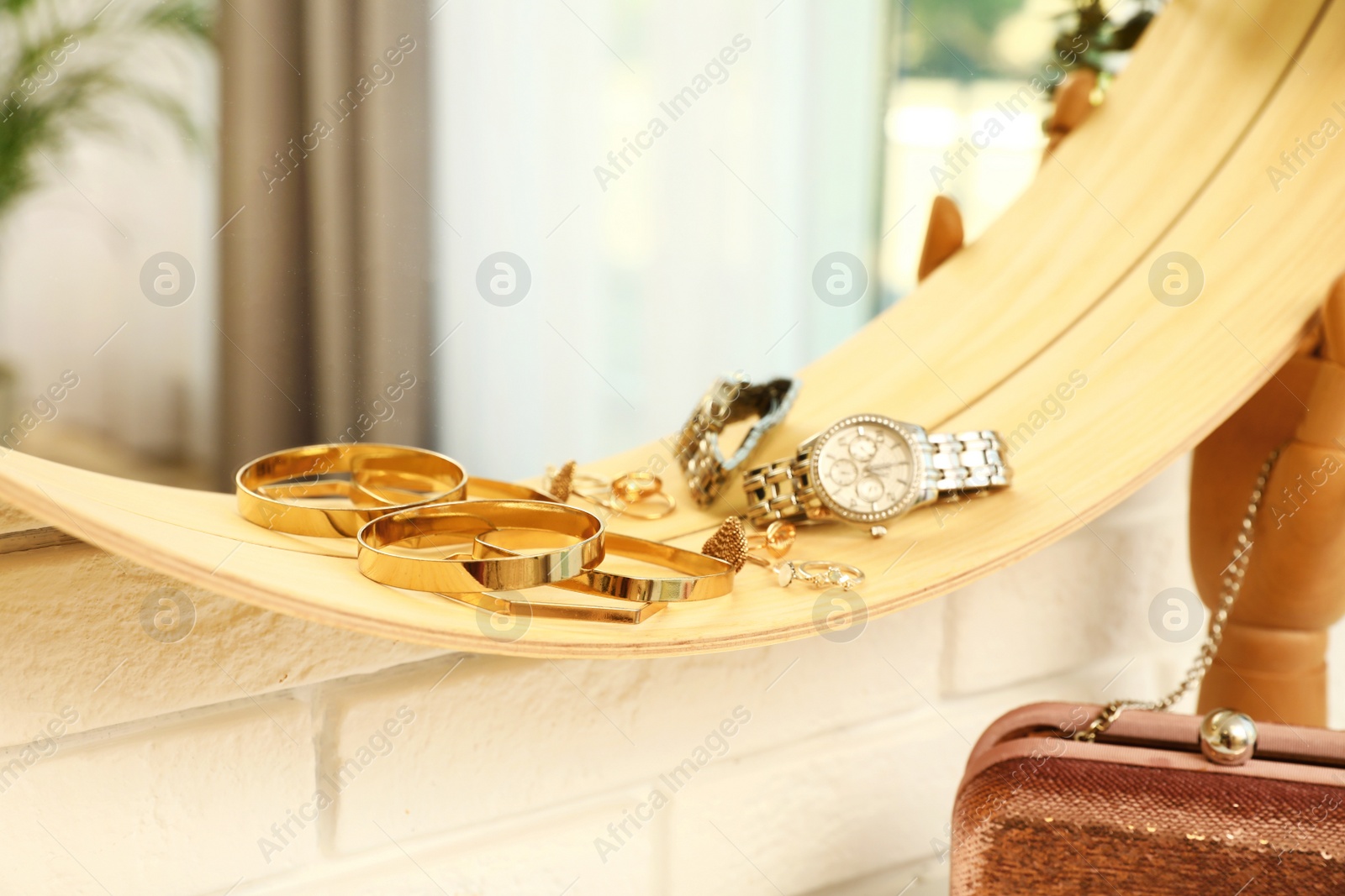 Photo of Round mirror with female accessories on brick wall indoors, closeup. Interior design