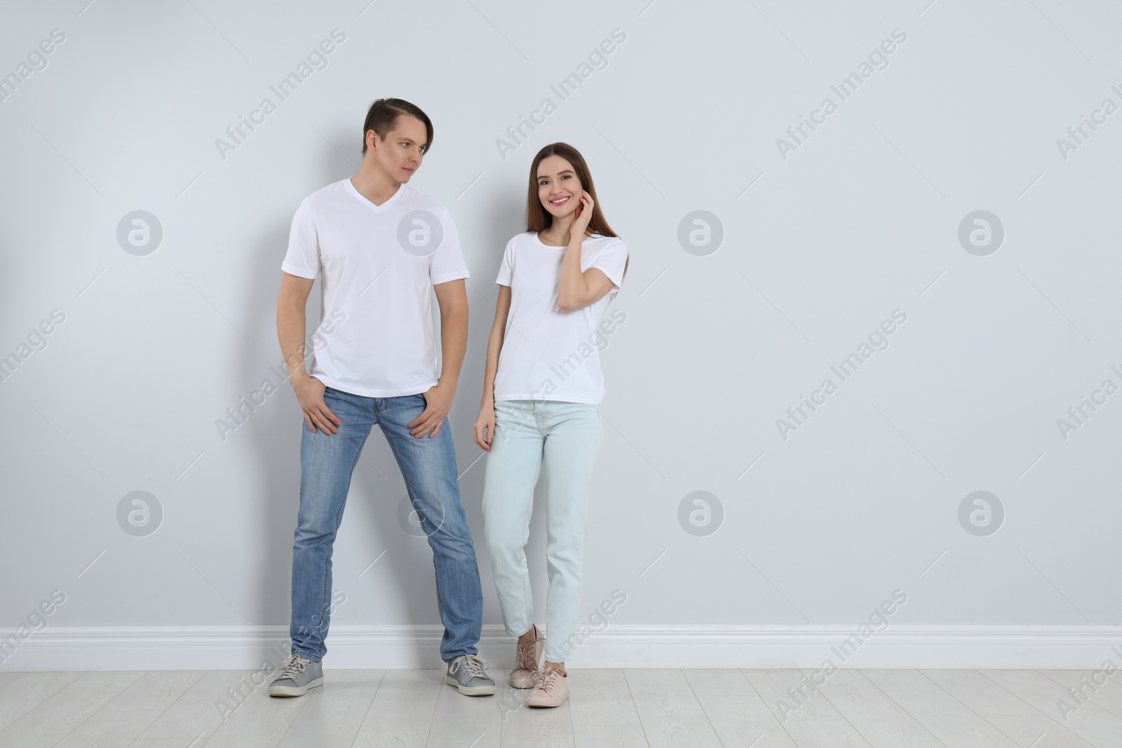 Photo of Young couple in stylish jeans near light wall