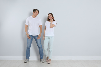 Young couple in stylish jeans near light wall