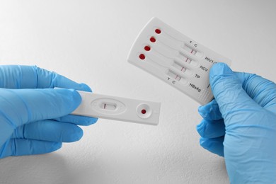 Photo of Doctor holding two disposable express tests at white table, closeup