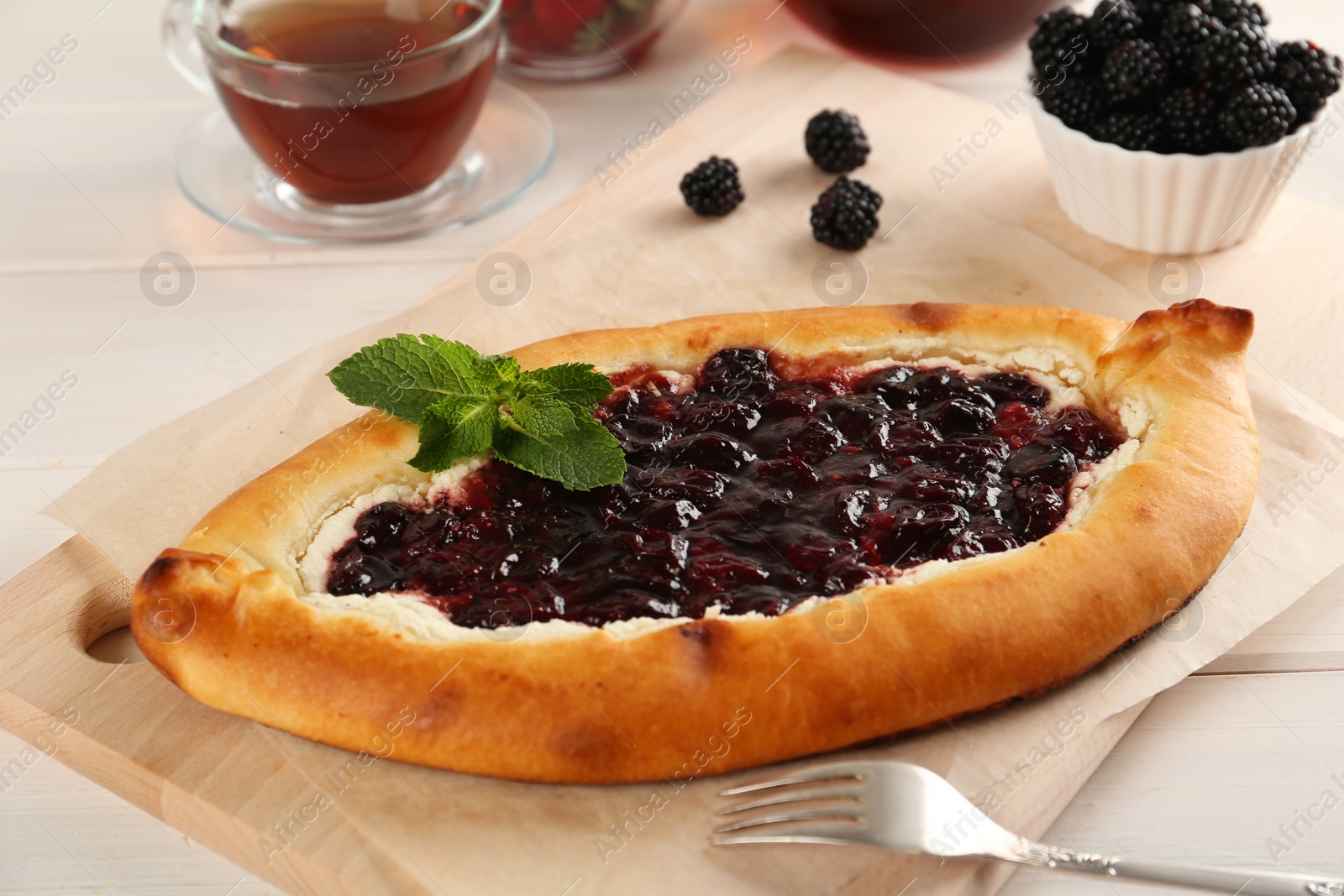 Photo of Delicious sweet cottage cheese pastry with cherry jam served on white wooden table