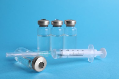 Photo of Disposable syringe with needle and vials on light blue background