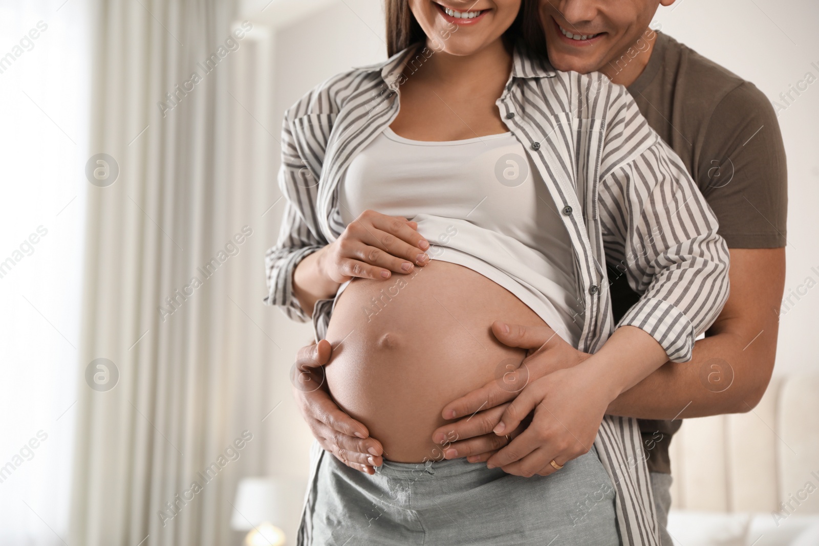 Photo of Young pregnant woman with her husband at home, closeup