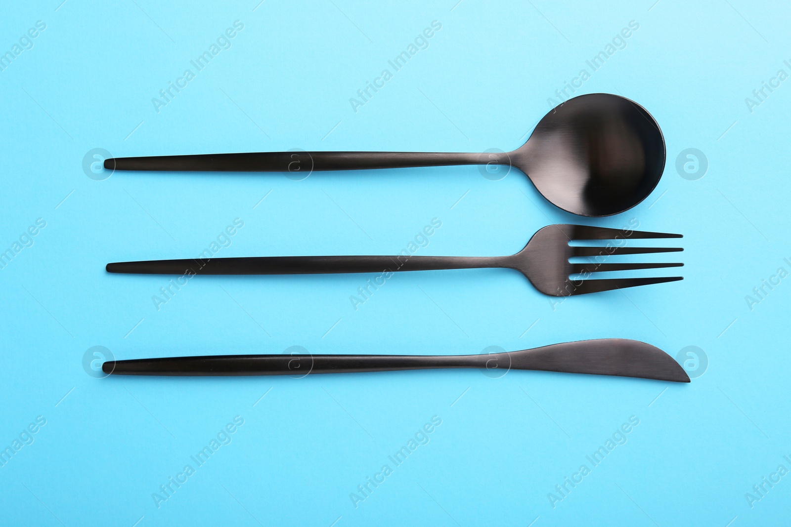 Photo of Stylish cutlery set on light blue table, flat lay