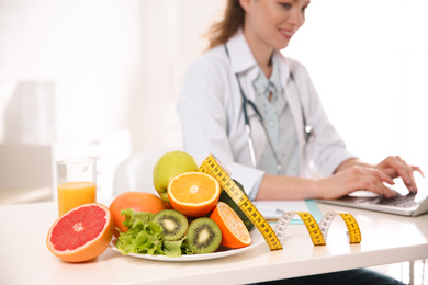 Healthy products, measuring tape and blurred nutritionist on background