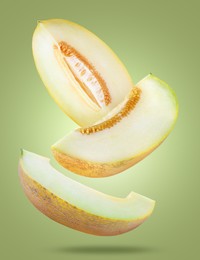 Image of Delicious ripe melon slices falling on olive color background