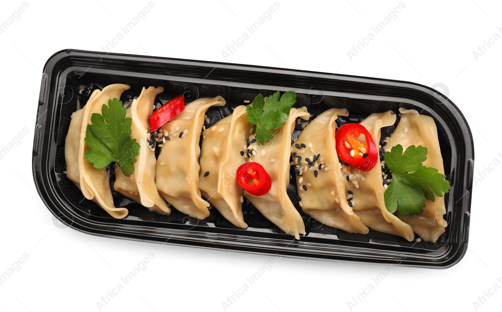 Photo of Delicious gyoza (asian dumplings) with sesame, parsley and pepper isolated on white, top view