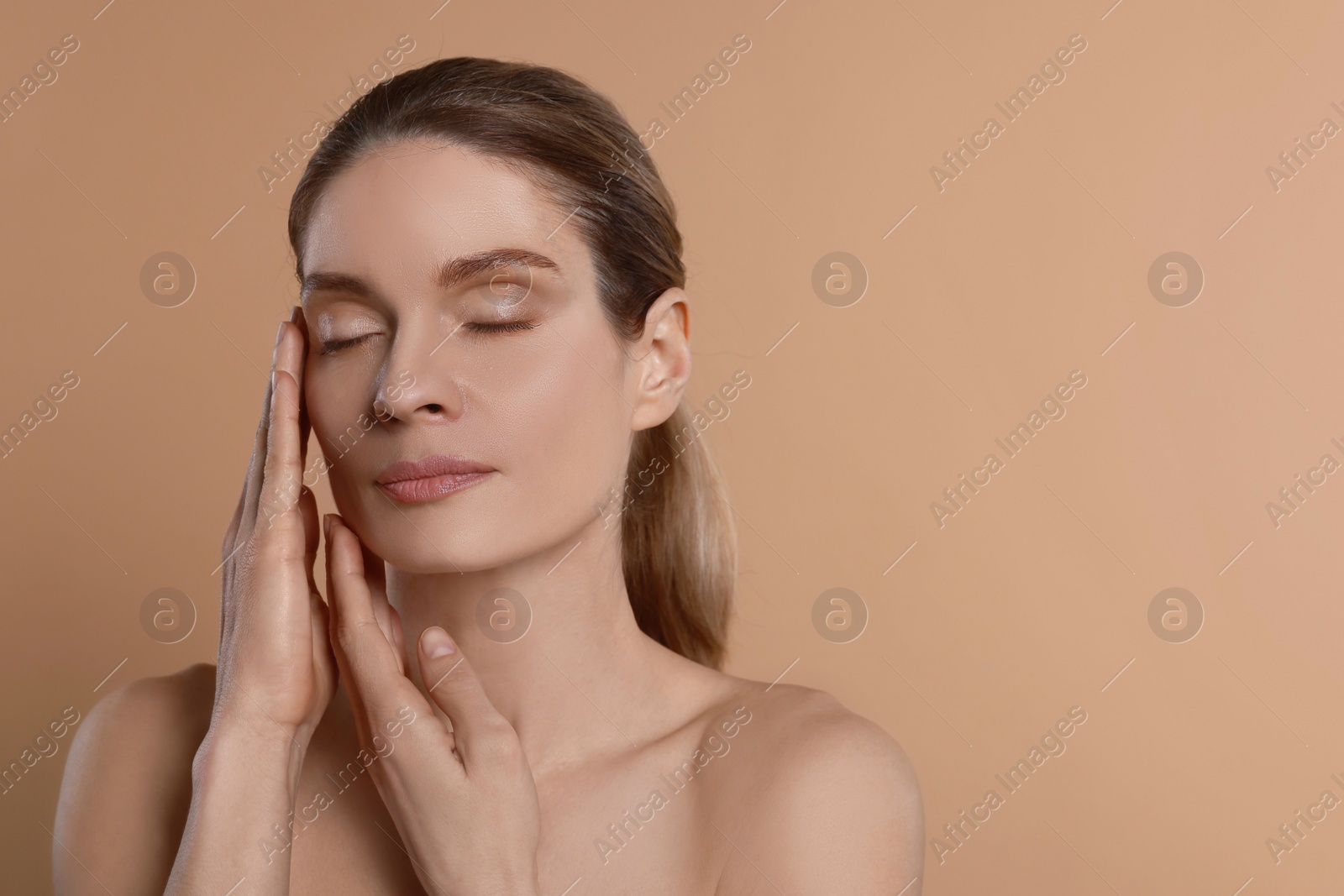 Photo of Woman massaging her face on beige background. Space for text