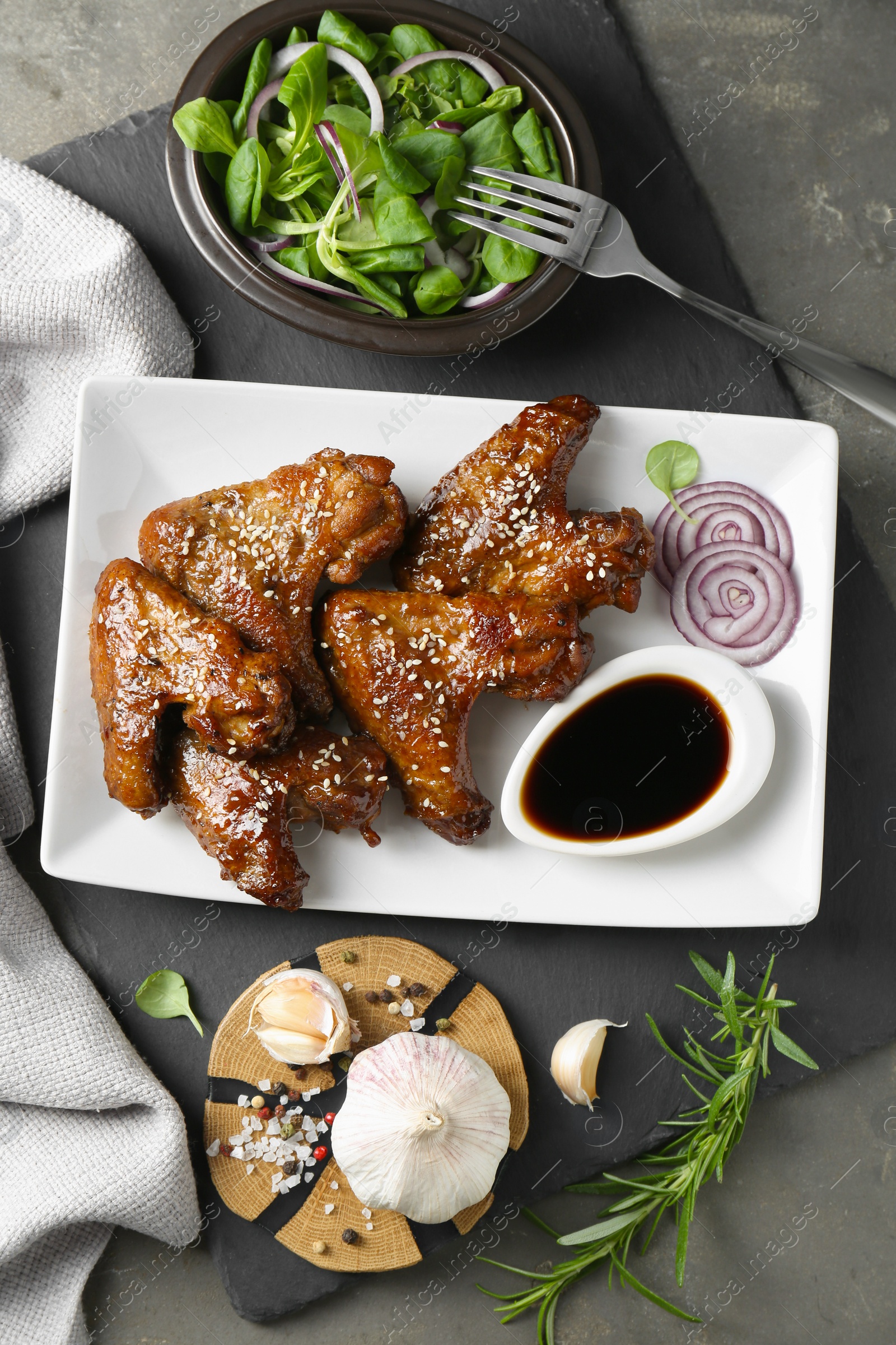 Photo of Chicken wings glazed with soy sauce served on grey table, flat lay