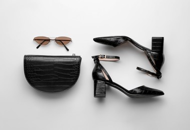 Photo of Stylish woman's bag, sunglasses and shoes on light background, flat lay