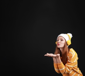 Photo of Young woman listening to music with headphones on black background, space for text