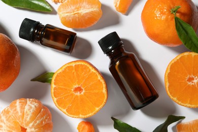 Photo of Aromatic tangerine essential oil in bottles and citrus fruits on white table, flat lay