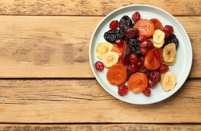 Mix of delicious dried fruits on wooden table, top view. Space for text