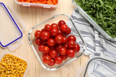 Photo of Containers with tomatoes and fresh products on wooden table, flat lay. Food storage