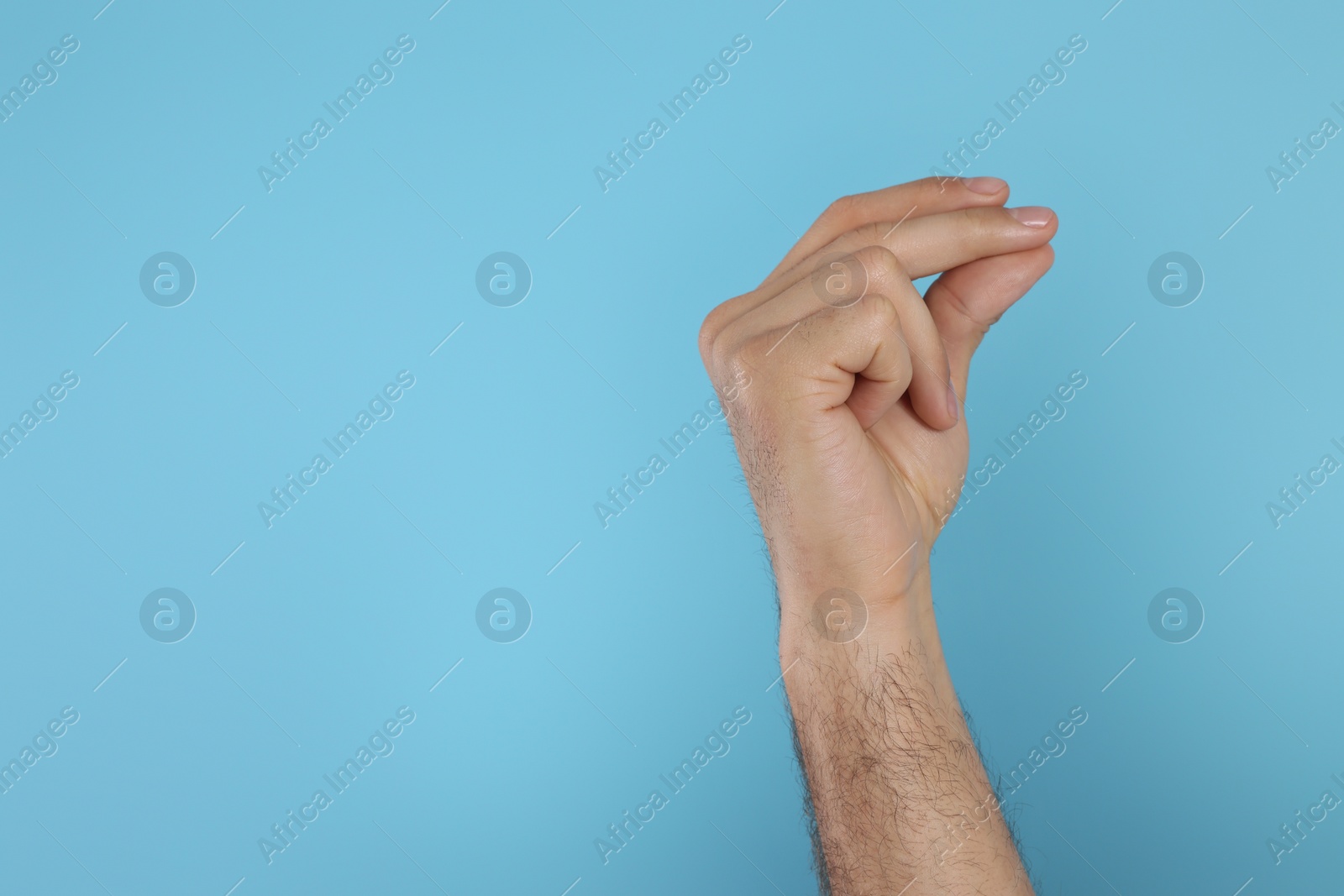Photo of Man snapping fingers on light blue background, closeup of hand. Space for text