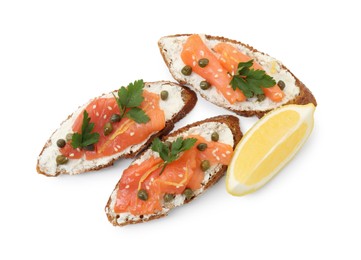 Photo of Tasty canapes with salmon, capers, lemon and cream cheese isolated on white, top view