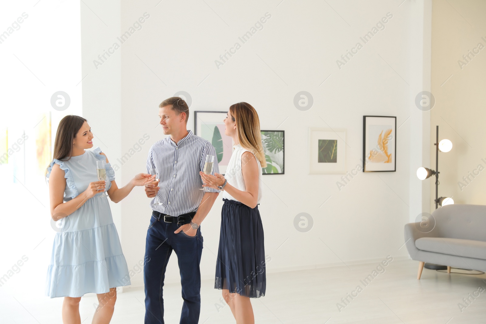 Photo of Group of people with glasses of champagne at exhibition in art gallery