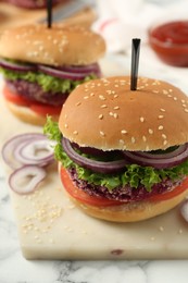 Photo of Tasty vegetarian burgers with beet patties on white marble table, closeup