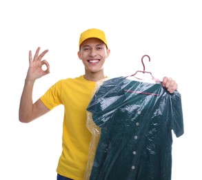 Photo of Dry-cleaning delivery. Happy courier holding dress in plastic bag and showing OK gesture on white background