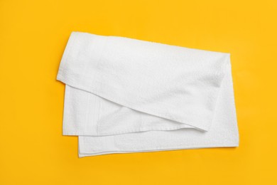 Photo of Folded white beach towel on yellow background, top view