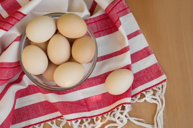 Photo of Fresh raw eggs and towel on wooden table, flat lay