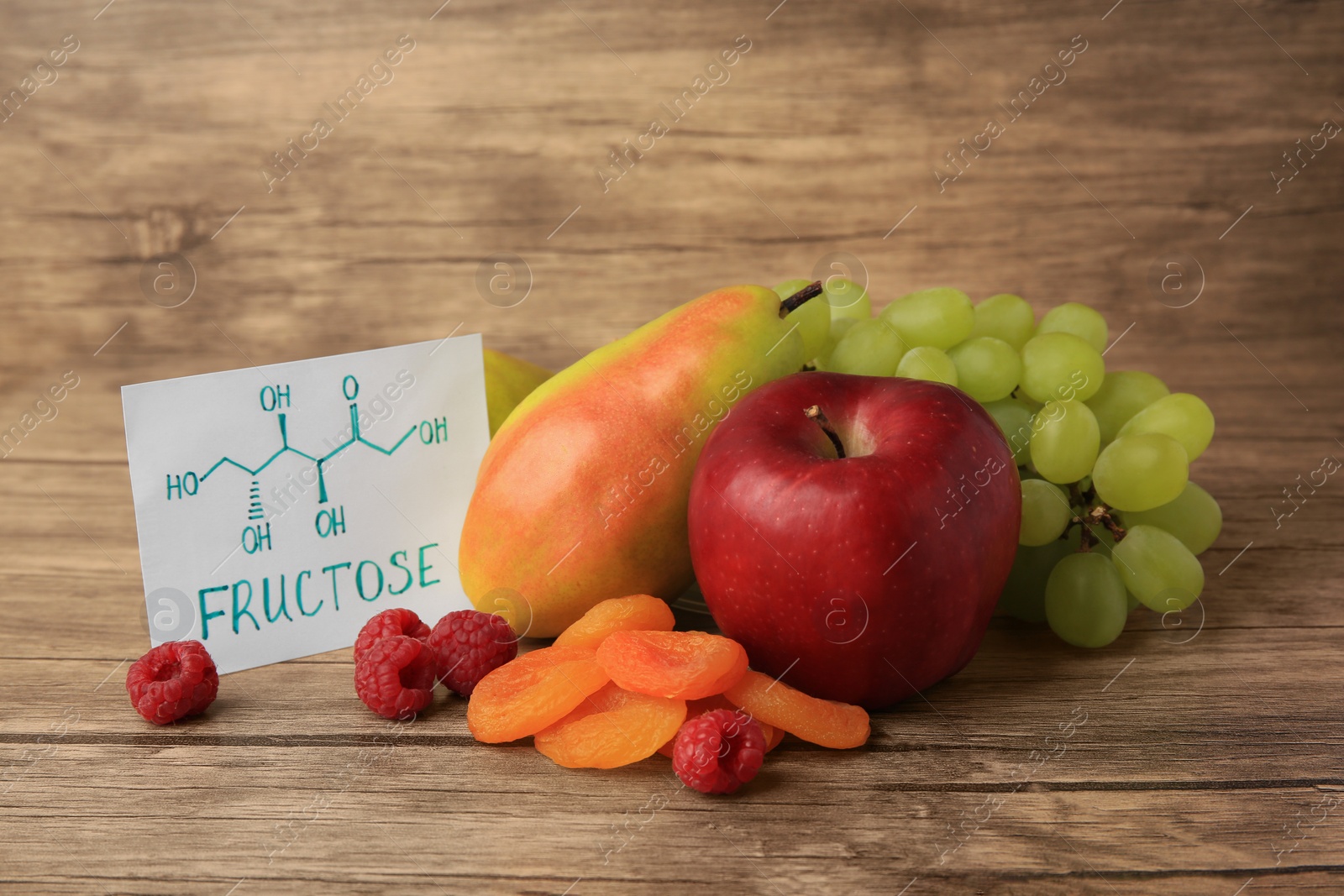 Photo of Card with word Fructose, delicious ripe fruits, raspberries and dried apricots on wooden table