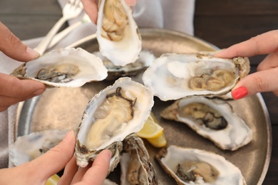 People with fresh oysters, focus on hands