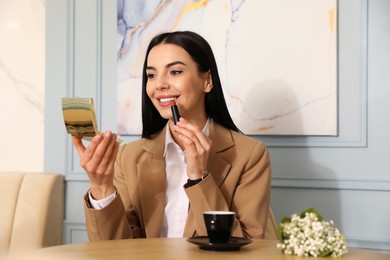 Woman fixing makeup at cafe in morning