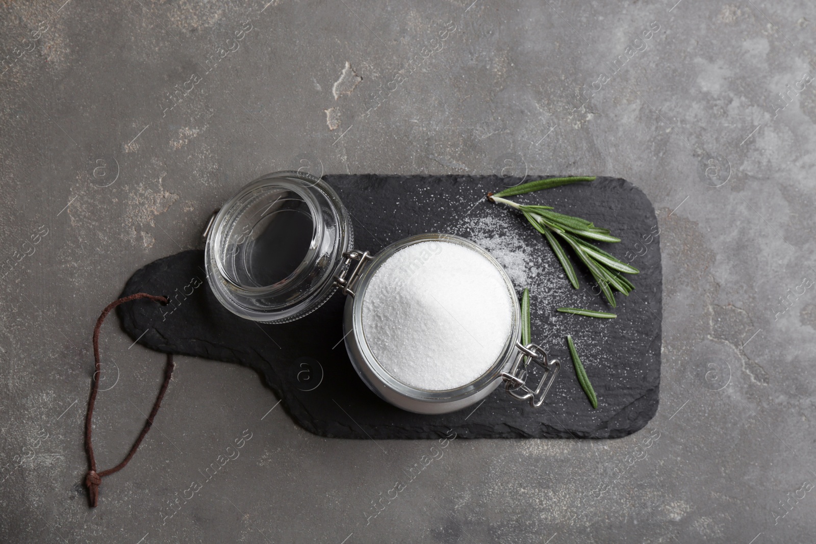 Photo of Natural salt and rosemary on grey table, top view
