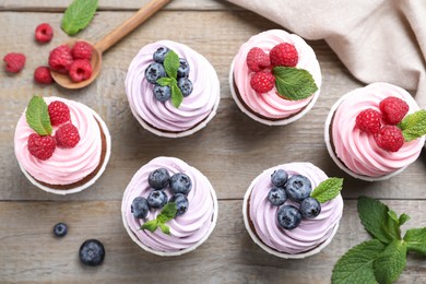 Sweet cupcakes with fresh berries on wooden table, flat lay