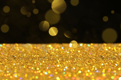 Photo of Many golden paillettes against black background. Space for text