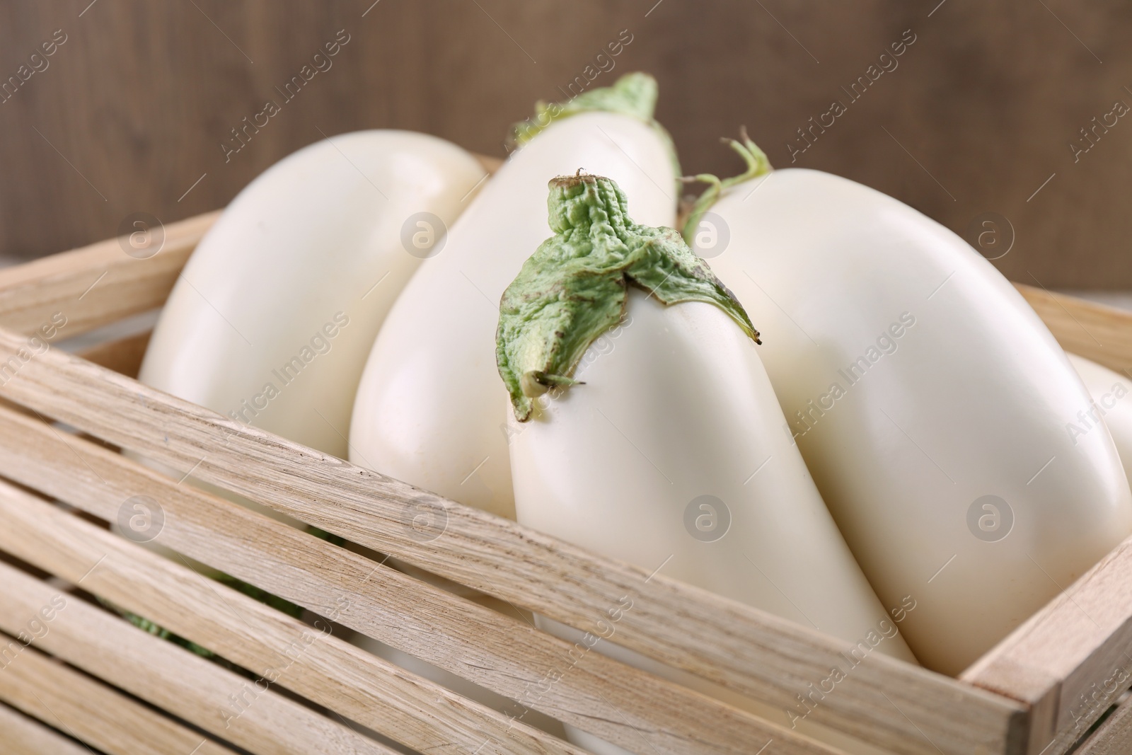 Photo of Fresh white eggplants in wooden crate, closeup