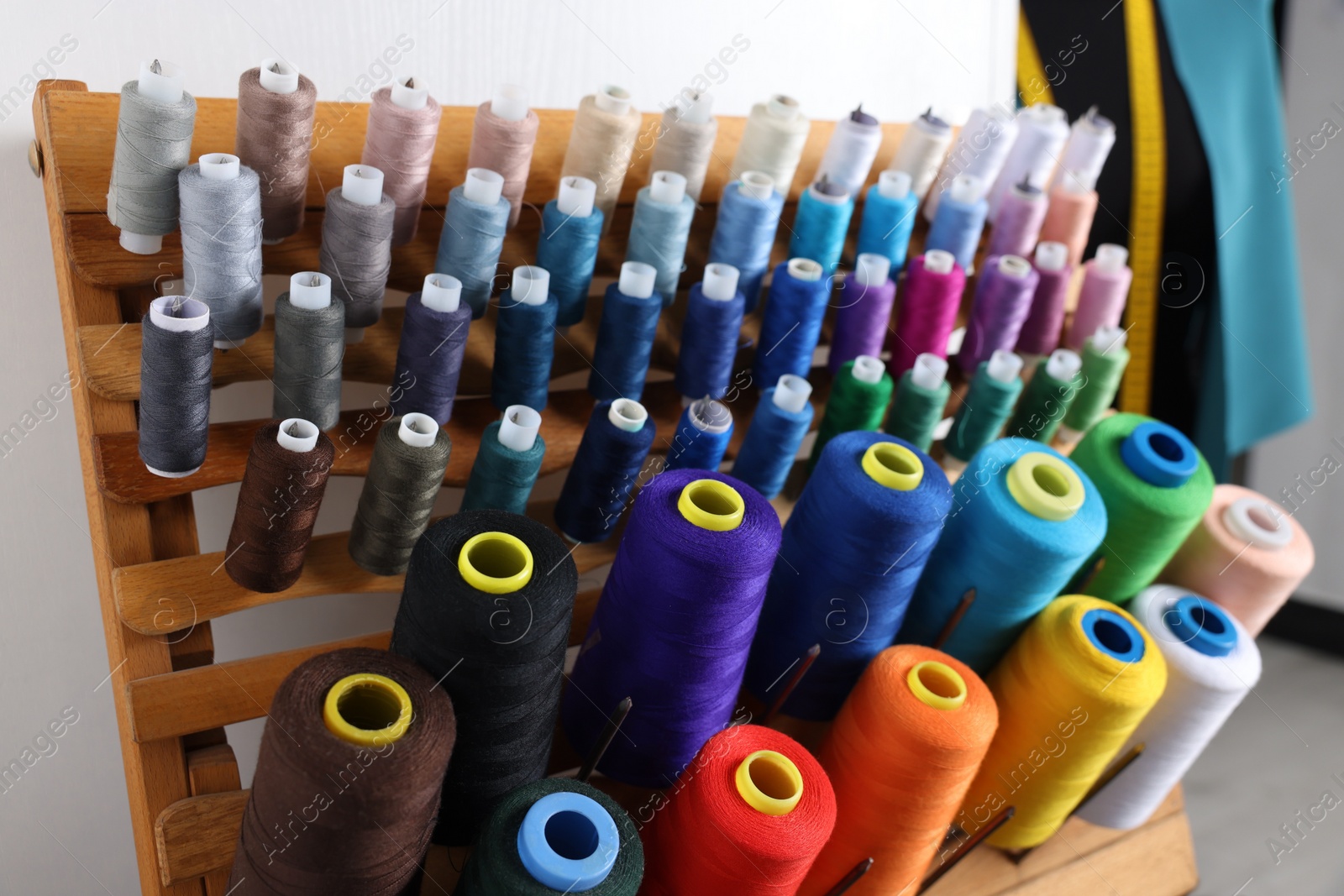 Photo of Set of colorful threads on stand in dressmaking workshop