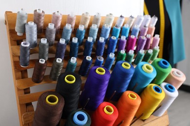 Photo of Set of colorful threads on stand in dressmaking workshop