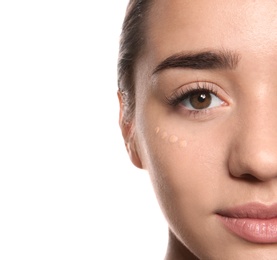 Young woman with liquid foundation on her face against white background, closeup