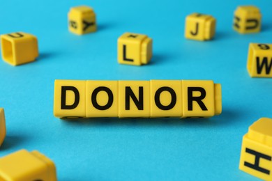 Photo of Word Donor made of cubes on light blue background