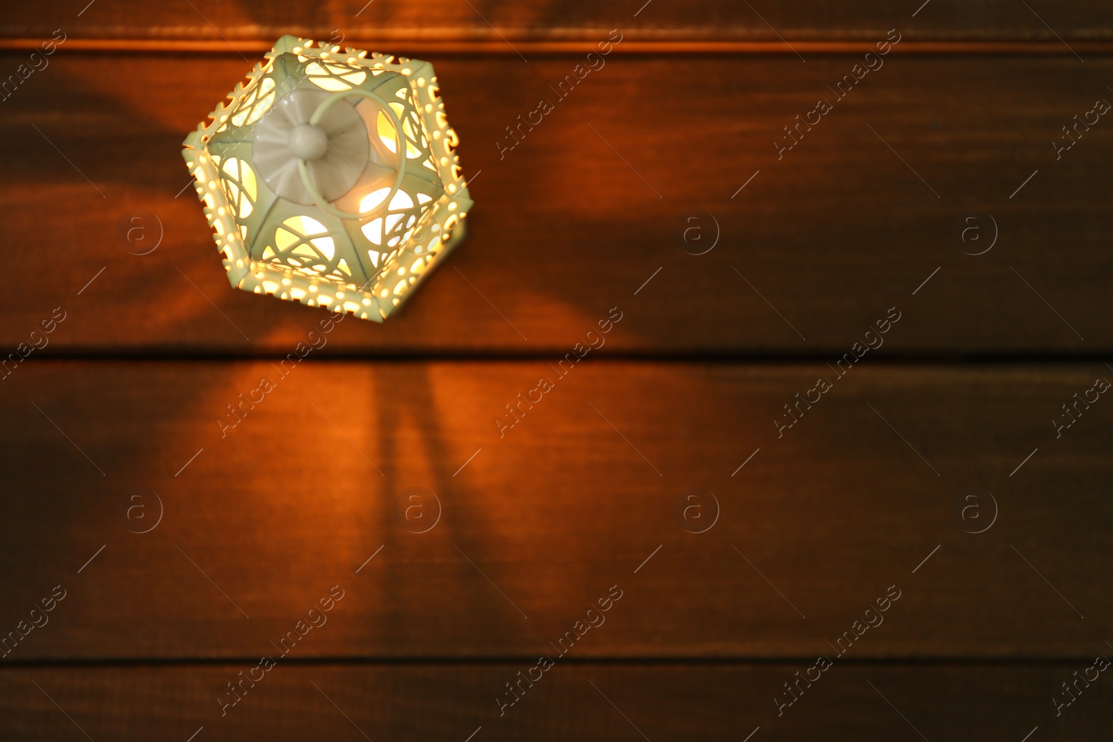 Photo of Decorative Arabic lantern on wooden table, top view. Space for text