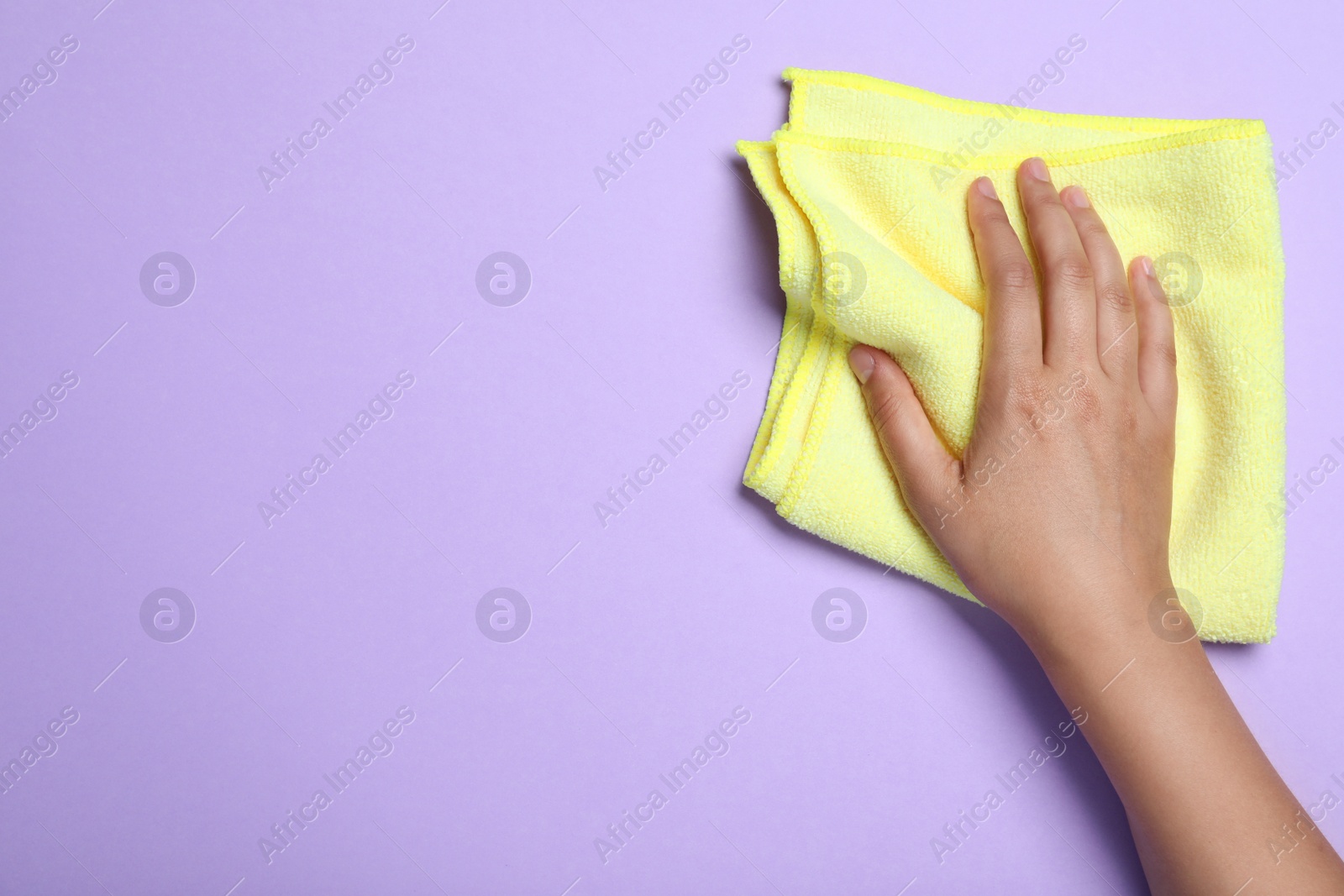 Photo of Woman with microfiber cloth on light background, top view. Space for text