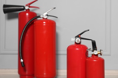 Red fire extinguishers near grey wall, selective focus